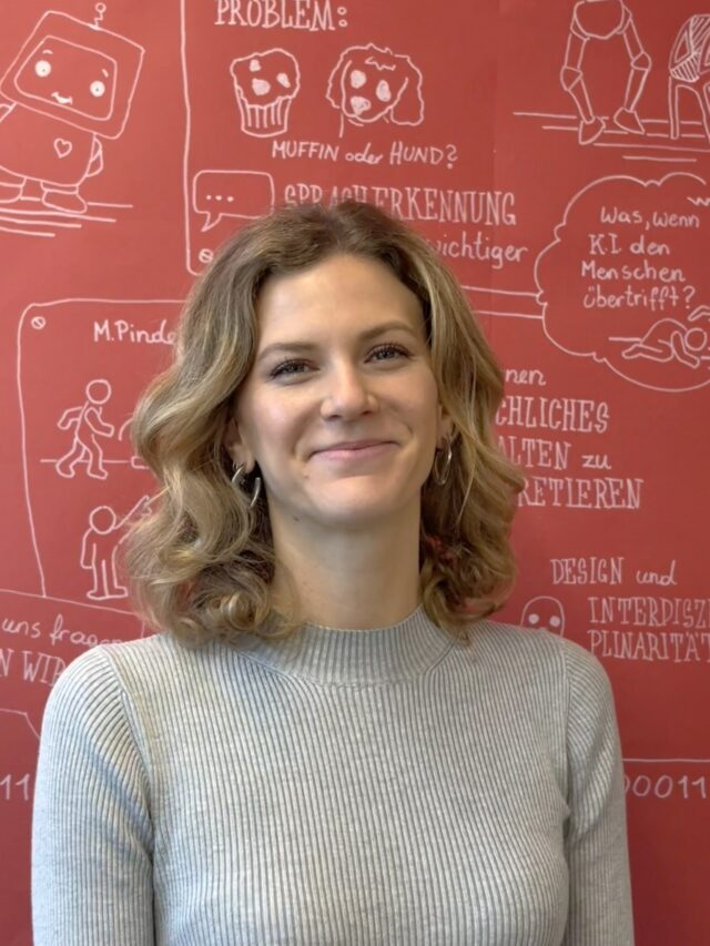 Eine Frau mit gewelltem blondem Haar, die ein hellgraues Oberteil trägt, steht lächelnd vor einer roten Wand mit weißen, handgezeichneten Illustrationen und deutschem Text.