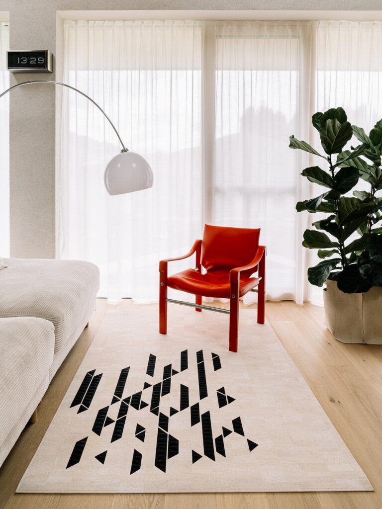 Teppich mit Rauten und Dreiecken und dahinter ein roter Sessel und eine Leselampe