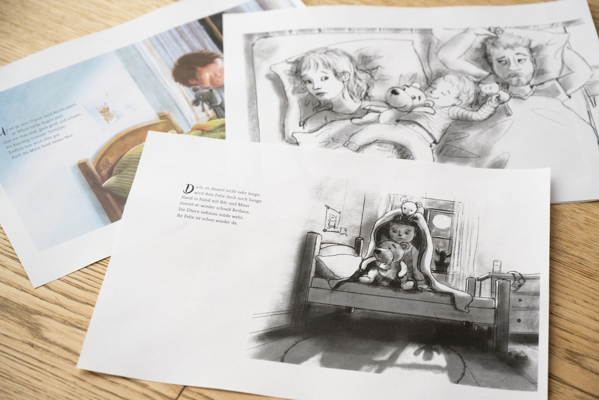Drei illustrierte Seiten aus einem Kinderbuch sind auf einer hölzernen Fläche ausgebreitet und zeigen Szenen eines Kindes im Bett, einige in Farbe, andere in Schwarz-Weiß, mit Erwachsenen und ausgestopften Tieren in der Nähe.