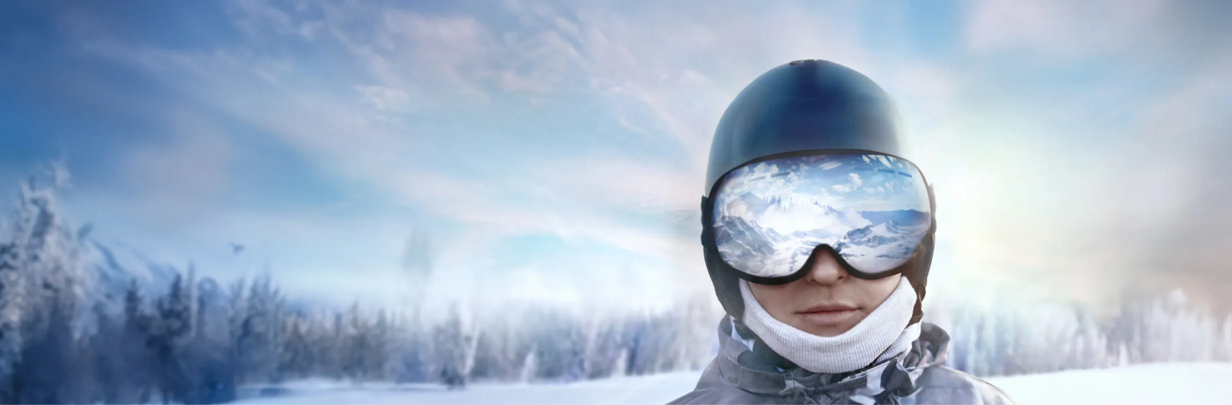 Eine Person, die einen Skihelm, eine Skibrille und Winterkleidung trägt, steht im Freien in einer verschneiten Landschaft. Die Reflexion der Schneelandschaft ist in ihrer Brille sichtbar, mit einem hellen Himmel im Hintergrund.